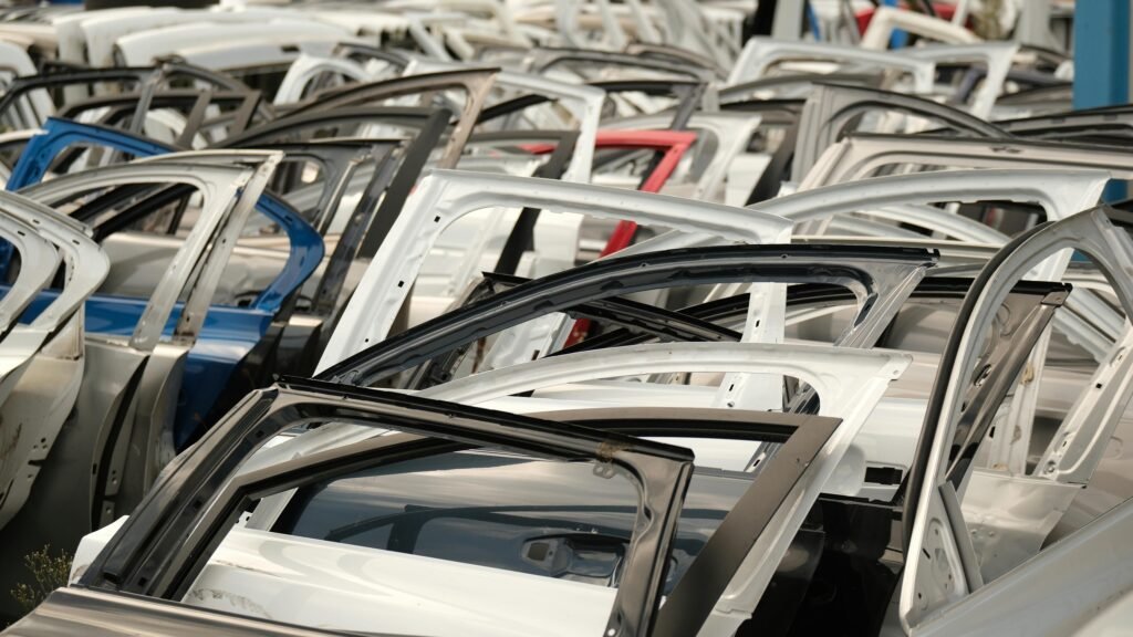 A variety of car doors in different colors arranged in a junkyard setting.
