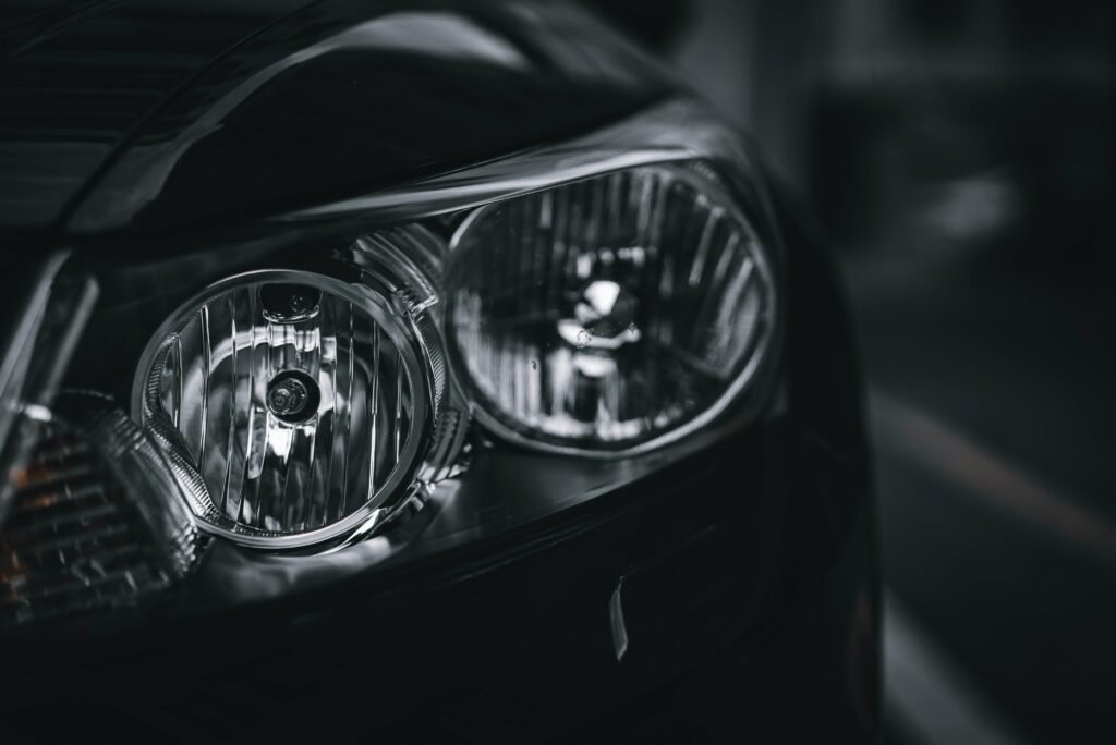 Detailed close-up of a car headlight showcasing design and texture in black and white.